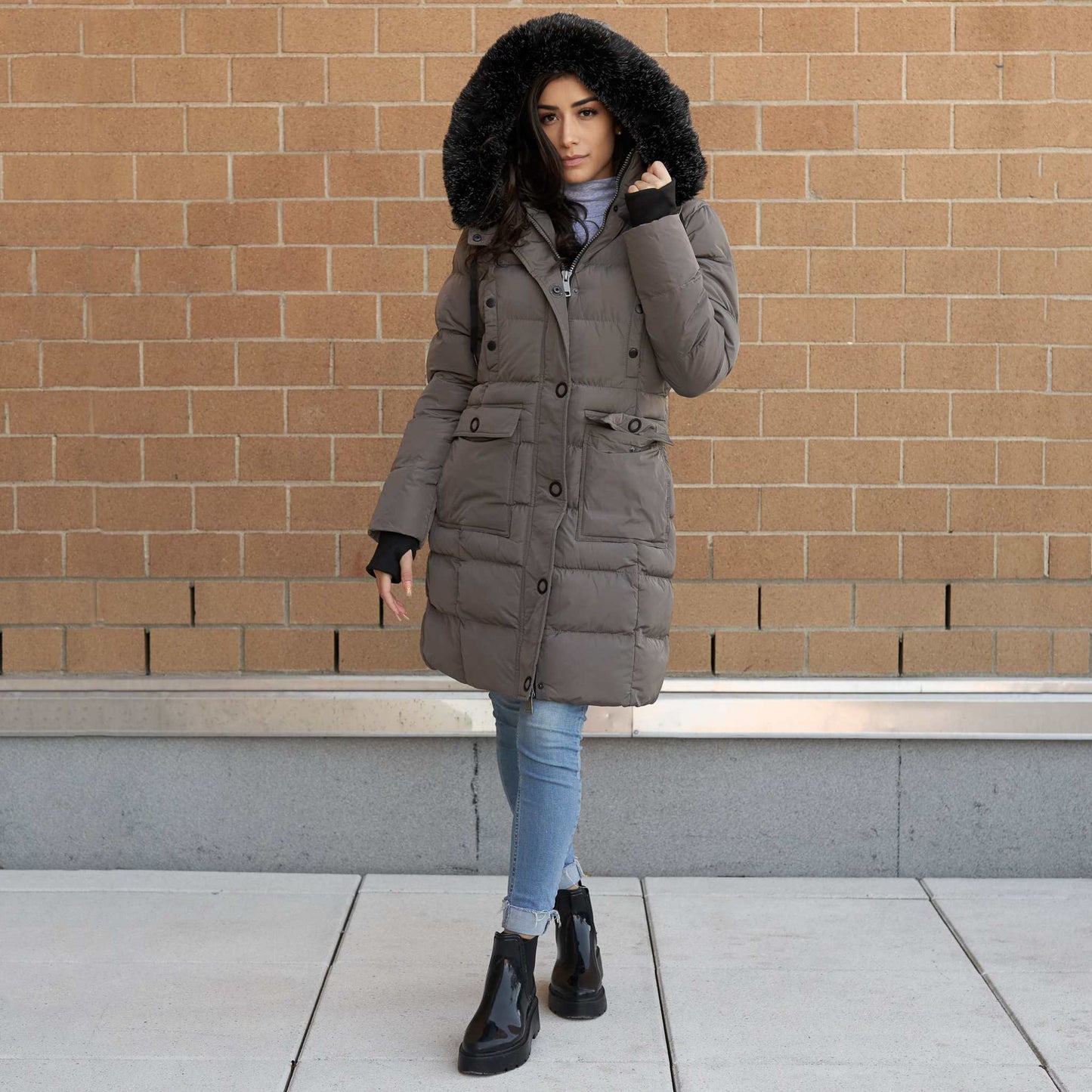 Heavy women's winter coat with faux fur hood, mid-length design, and cargo pockets, perfect for cold weather.